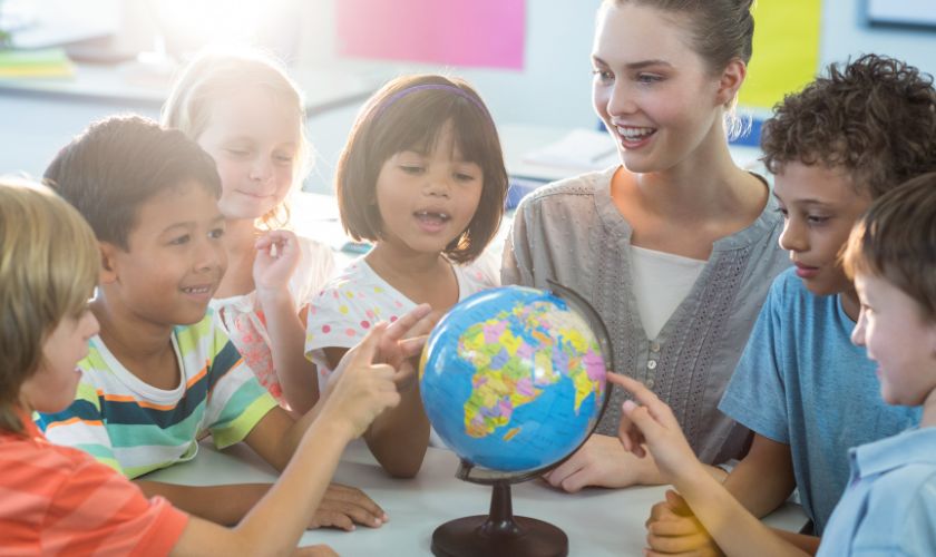 Učiteljica objašnjava geografiju djeci na globusu